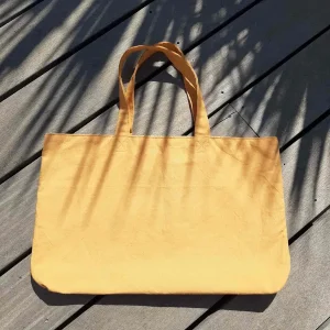 Sac cabas en tissu jaune, avec anses assorties.