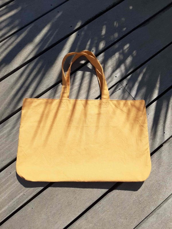 Sac cabas en tissu jaune, avec anses assorties.