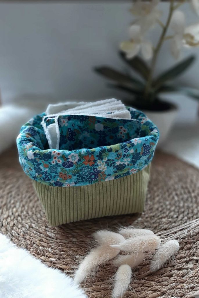 Petite panière en tissu vert contenant des lingettes textiles assorties.