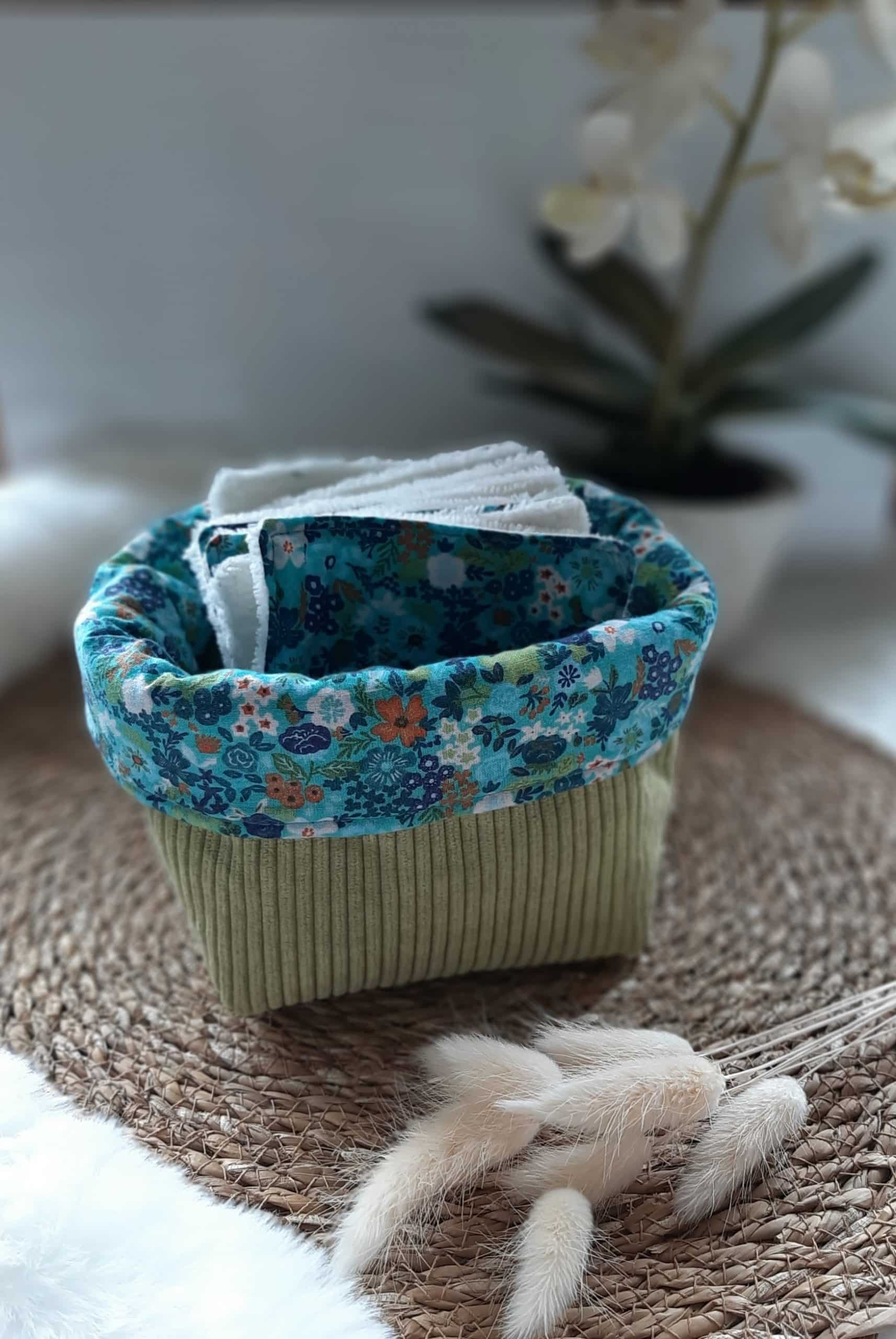Petite panière en tissu vert contenant des lingettes textiles assorties.