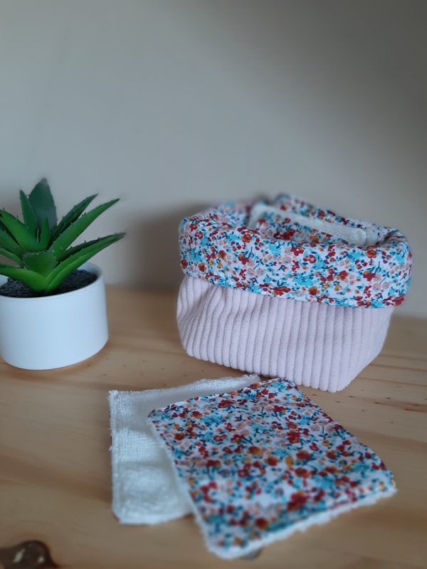 Petite panière en tissu rose contenant des lingettes textiles assorties.