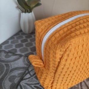 Zoom sur les languettes latérales de la trousse Essentiel, cousues avec soin pour une ouverture facile et une finition élégante.