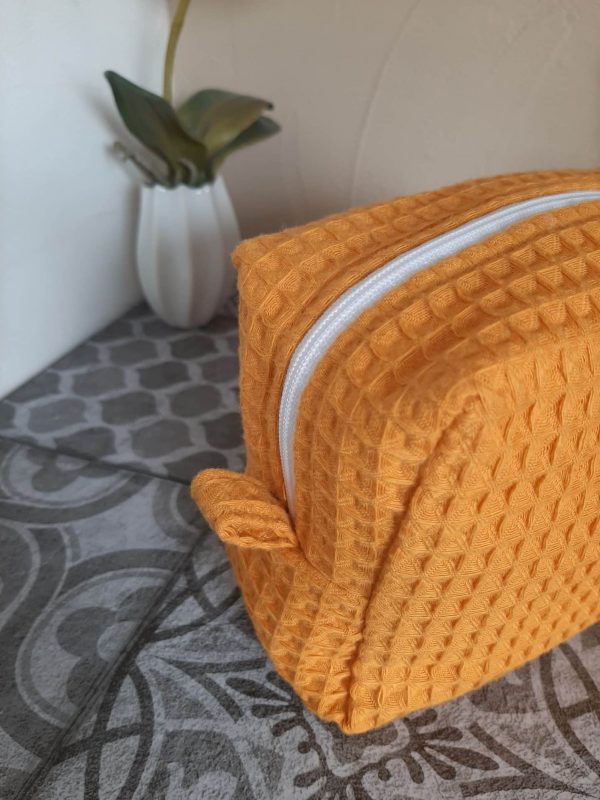Zoom sur les languettes latérales de la trousse Essentiel, cousues avec soin pour une ouverture facile et une finition élégante.