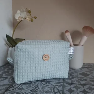 Trousse Essentiel en nid d'abeille vert d'eau, format compact avec zip doré et anse latérale. Un accessoire sobre et pratique pour ranger ses indispensables.