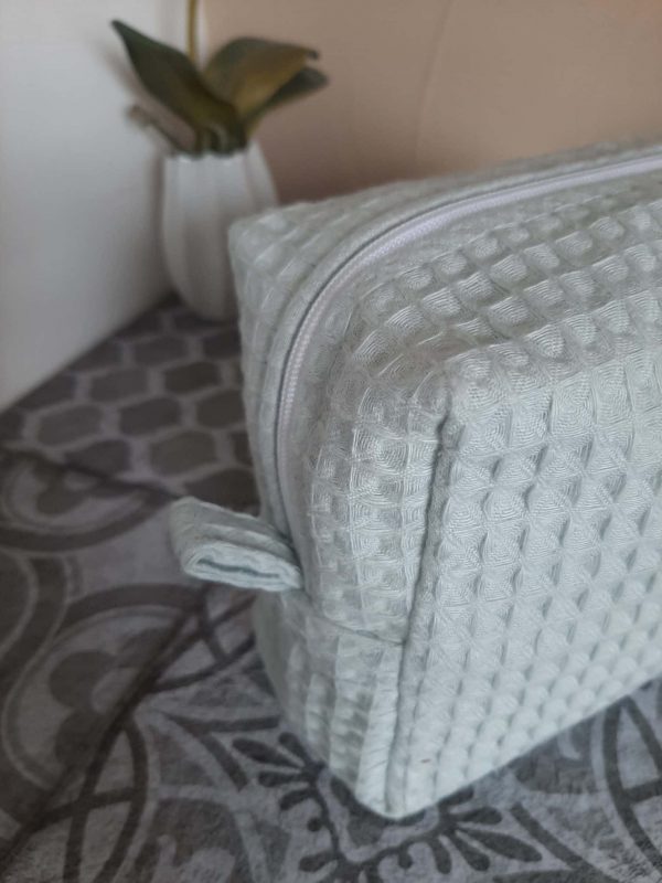Zoom sur les languettes latérales de la trousse Essentiel, cousues avec soin pour une ouverture facile et une finition élégante.