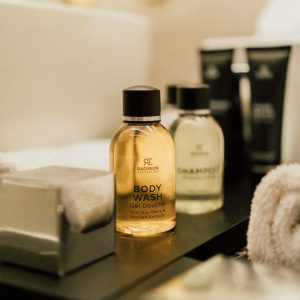Produits de soin alignés sur un meuble de salle de bain, avec gel douche, shampoing et serviette