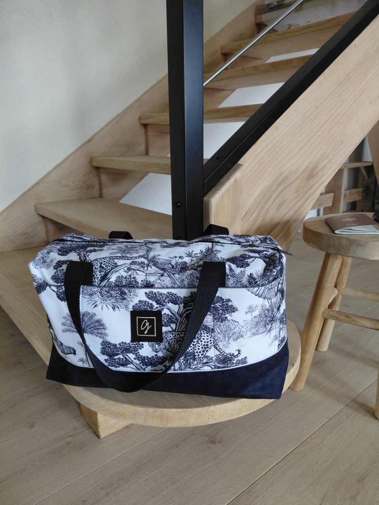Sac week-end en toile imprimée sauvage, posé sur un escalier moderne