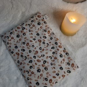 Bouillotte sèche aux grains de riz en coton motif léopard posée sur un plaid doux avec une bougie allumée – La P’tite Garçonnière
