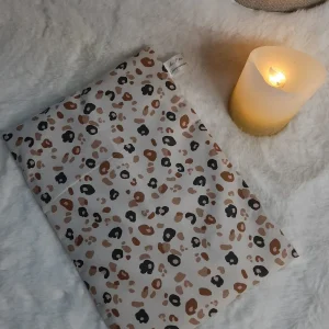 Bouillotte sèche aux grains de riz en coton motif léopard posée sur un plaid doux avec une bougie allumée – La P’tite Garçonnière